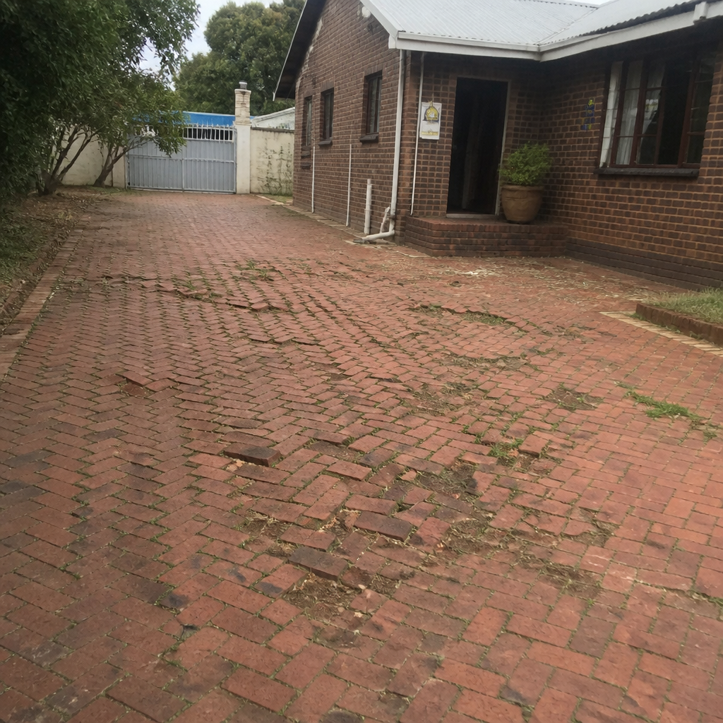 Clay brick driveway with sunken wheel tracks, tipped pavers standing proud of their neighbours and weeds growing through washed-out joints